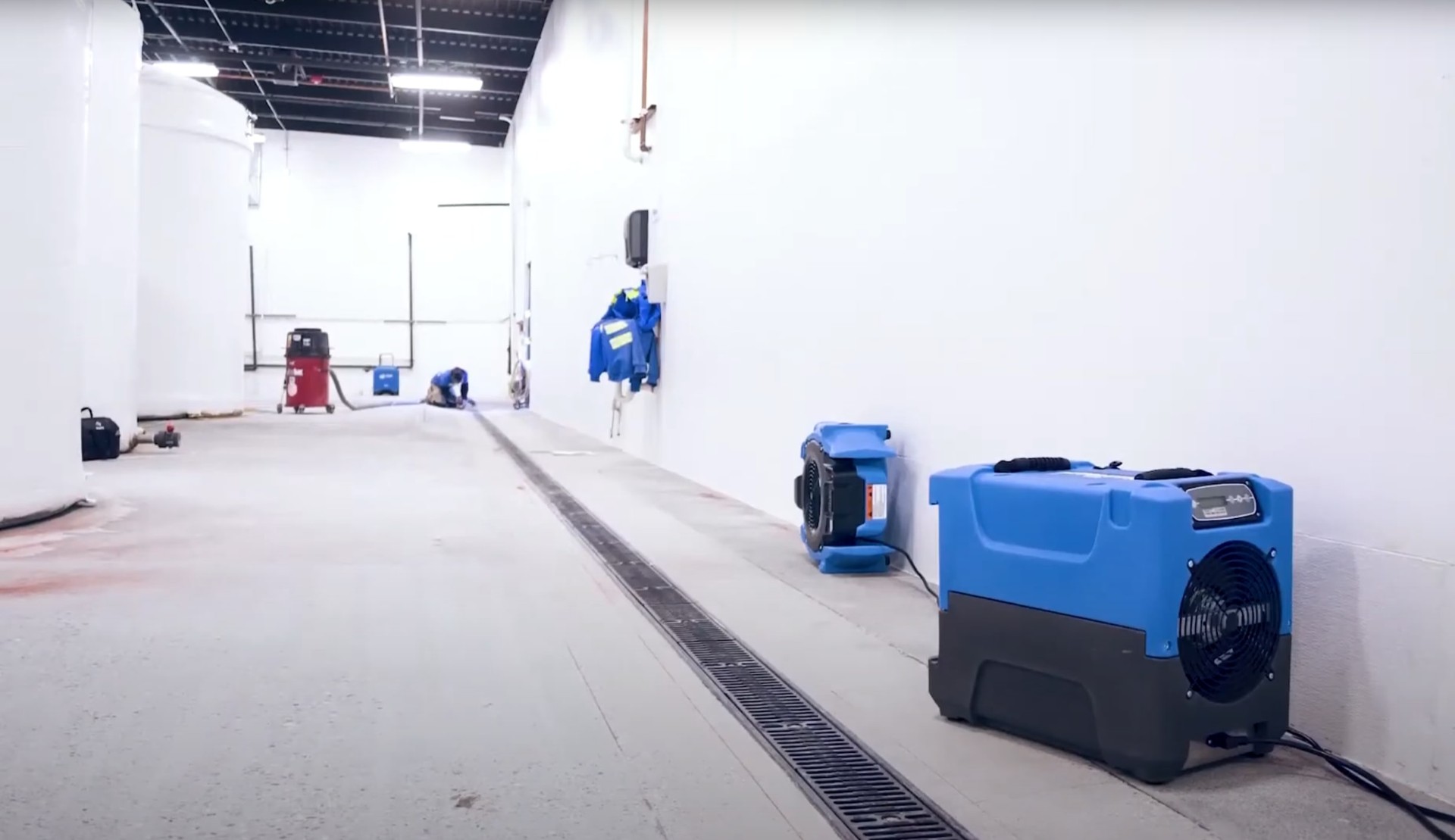 Water damage restoration equipment including air movers and dehumidifiers set up in a commercial space for professional drying